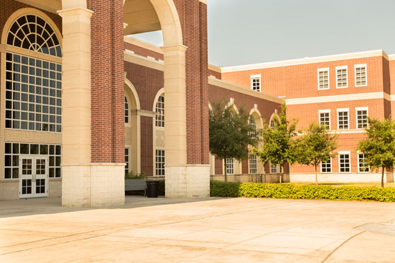 A sun-lit college campus with brick buildings and landscaping.